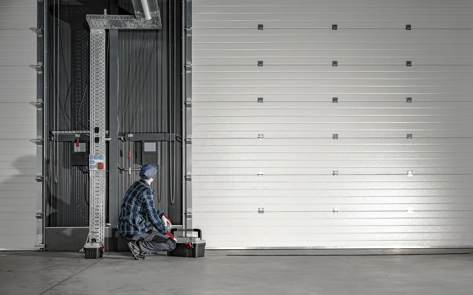 man in bending position looking at side of large garage door