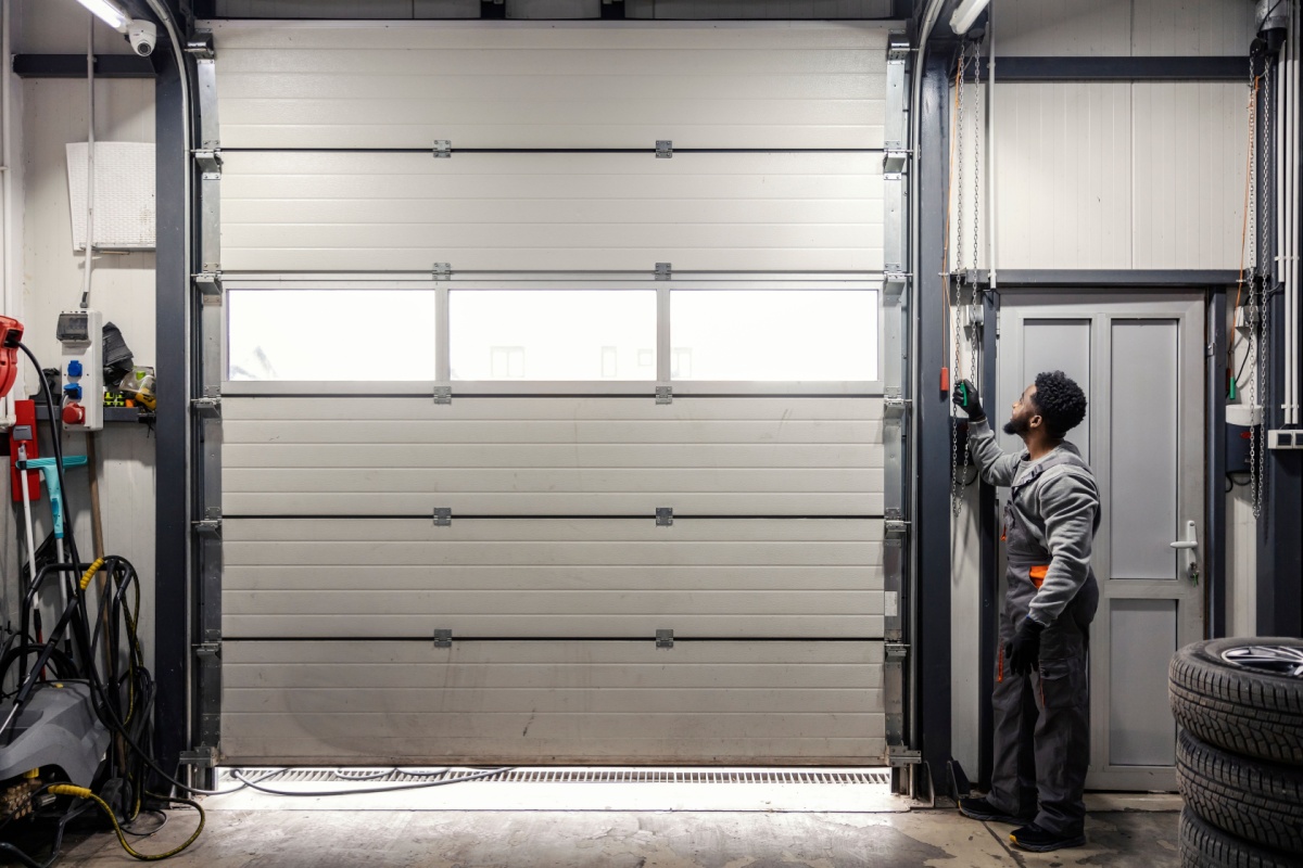 A mechanic opening an overhead door in a car repair shop